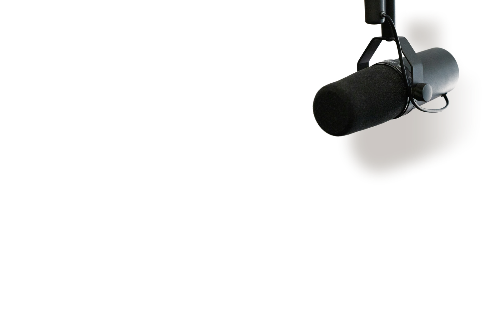 A broadcast microphone hanging from a boom arm, casting a shadow